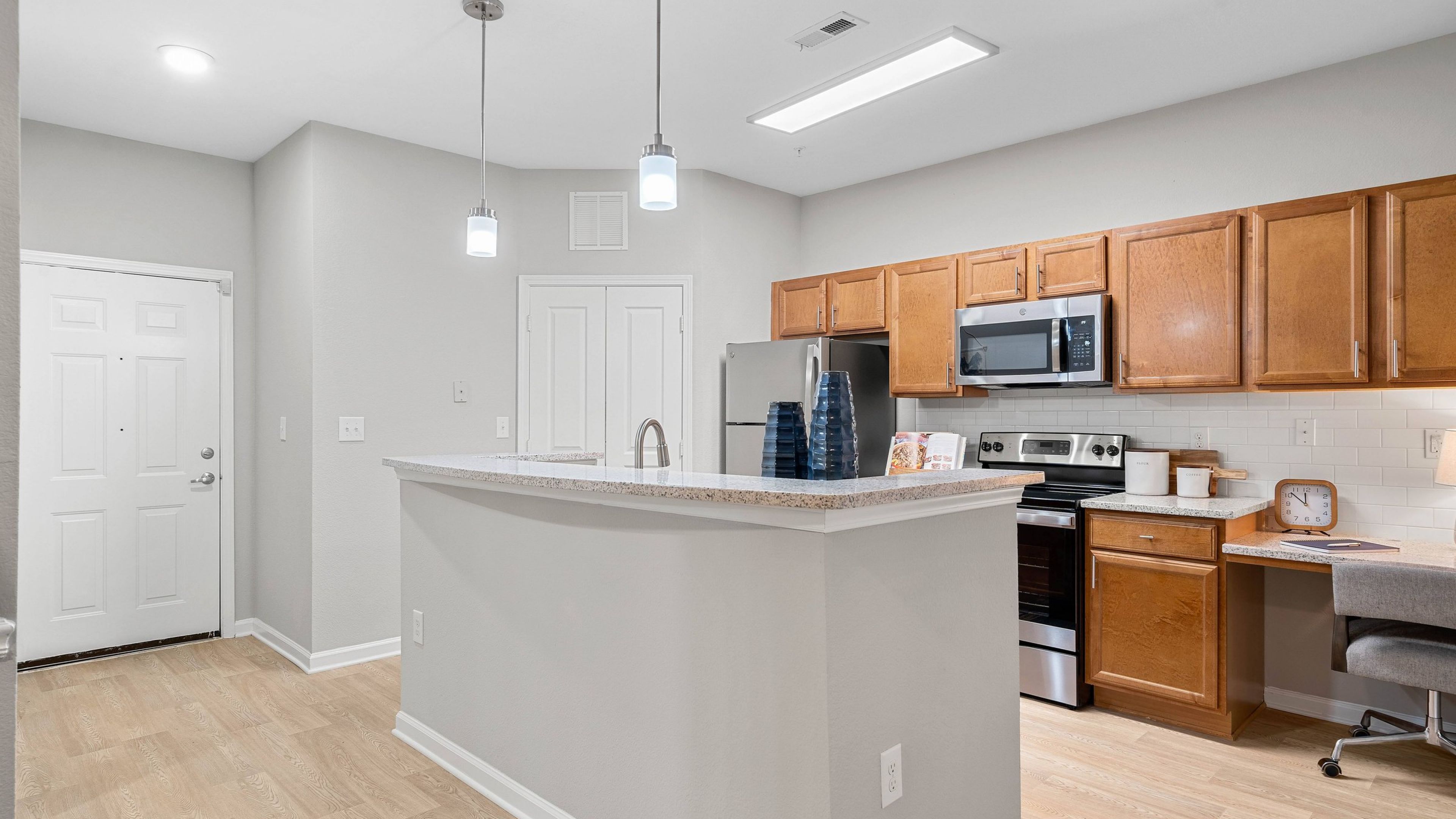 Hawthorne at the Greene apartment kitchen area with island, stainless steel appliances, and unique built-in desk nook