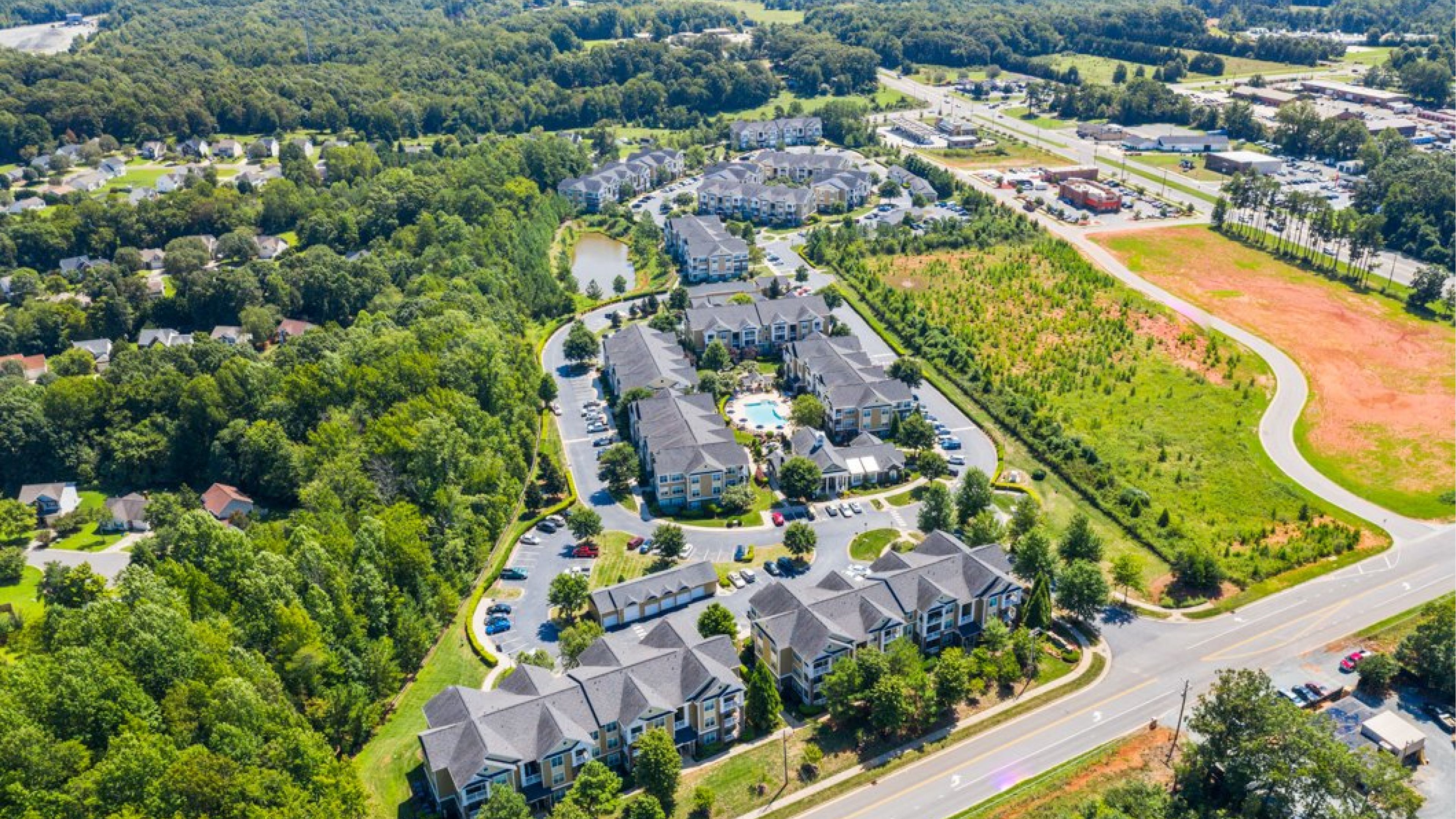 Hawthorne at the Greene beautiful aerial view of apartment community buildings, outdoor pool, and outdoor amenities, surrounded by green land and trees